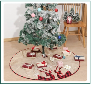 Detailed view of burlap Christmas tree skirt with reindeer pattern under a snowy tree