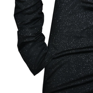 Detail view of black dress featuring shiny silver glitter fabric and ruched sleeve design