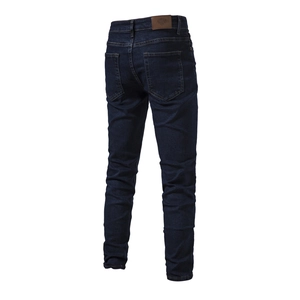 Detail of dark blue denim jeans showing back pockets and premium leather waist label