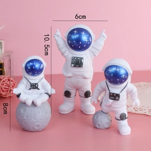 Three astronaut cake topper figures in white suits for space themed birthday party decor