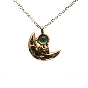Goldene Astronauten-Halskette mit Mond-Anhänger und blauem Edelstein auf weißem Hintergrund
