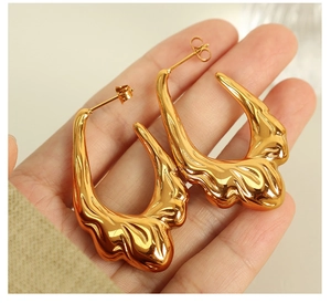 Detailed view of hollow lava style gold earrings with organic fluid texture on a palm
