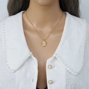 Close-up of golden double-layered snake chain with oval cat-eye stone pendant