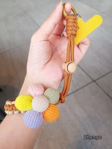 Macro shot of colorful handmade knitted flower phone lanyard with braided cord and metal hook