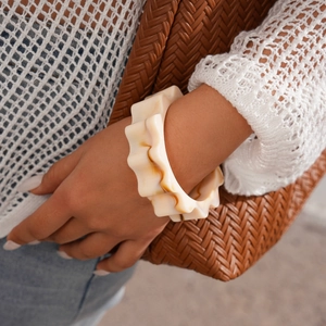 Macro shot of wide marble acrylic cuff with wavy gear edges worn by a model
