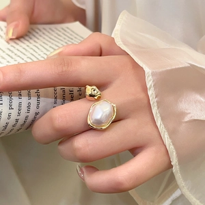 Detail of vintage irregular gold ring with baroque pearl on female index finger