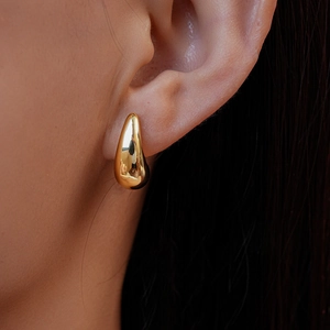Close-up of golden polished drop earrings showing high shine finish and sleek curved design