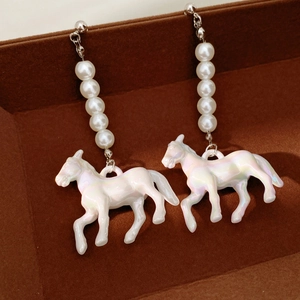 Detail of horse-shaped pearl earrings on a dark brown velvet jewelry display tray