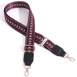 Adjustable burgundy woven bag strap with white arrow patterns and gold metal buckles