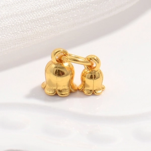 Macro view of gold-plated twin lily of the valley bell pendants with polished finish