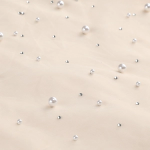 Detailed view of delicate beige mesh fabric with beads and shiny rhinestones