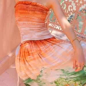 Detail of gradient orange pleats and green floral print on backless strapless dress
