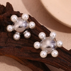 Macro shot of 18K gold plated steel earring with pearls on dark wood texture background