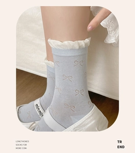 Detail of light blue crew socks with pink bows, frilly white edges and Mary Jane shoes