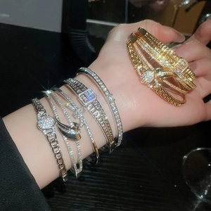 Détail de bracelets dorés et argentés avec zircons et fermoirs carrés sur poignet
