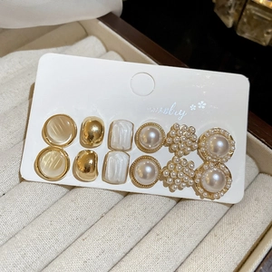 Detailed close-up of 6 pairs of gold-plated earrings with pearls and opal resin inserts