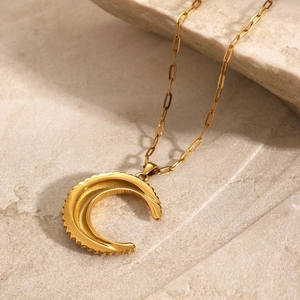 Détail du pendentif lune dorée avec bords texturés sur une fine chaîne assortie