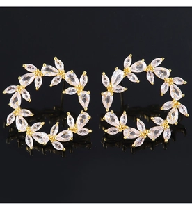 Macro shot of gold floral hoop earrings with crystal zircon in a water drop leaf pattern