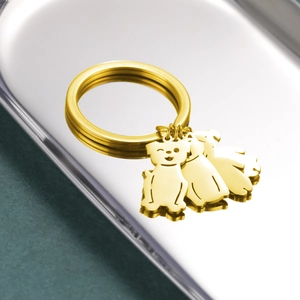 Polished gold dog-shaped charms on a stainless steel keychain over a silver metallic tray