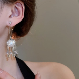 Detail of silver tassel earrings with pearl star charms and sparkling crystal droplets