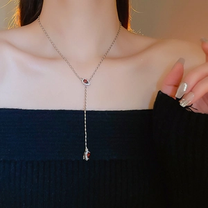 Detail of silver Y-shaped tassel necklace with red teardrop stone on model