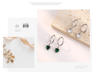 Détail de boucles d'oreilles cœur en argent avec zircons blancs et verts sur pierre