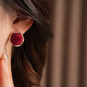 Close-up of red flocked geometric heart earring with gold metallic trim on a model