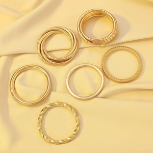 Detailed view of gold multi-layer spiral bracelets on soft beige satin fabric background