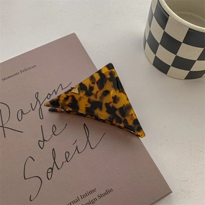 Close-up of tortoise shell triangle hair claw clip on a French book and ceramic cup