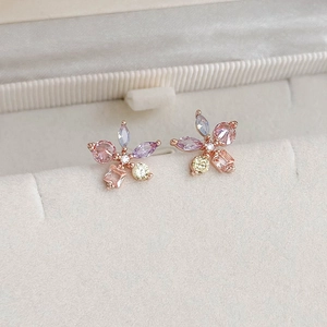 Macro shot of colorful zircon flower earrings on beige velvet in a luxury jewelry box