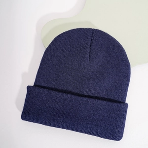 Detail shot of a dark purple knitted beanie with fine ribbed texture on a white background