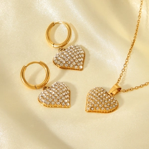 Detailed view of luxury gold heart jewelry set with sparkling crystals on silk