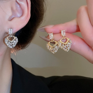 Close-up of geometric heart drop earrings with pave zircons and crystal details