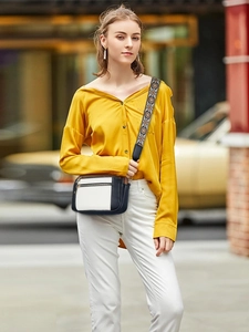Crossbody bag with colorful embroidered woven strap and multi-zipper detail on model