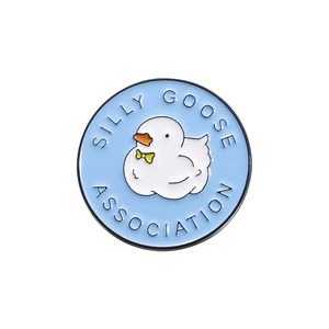 Round blue enamel pin with cartoon goose and Silly Goose Association text in white