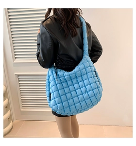 Sky blue quilted puffer hobo bag shown on shoulder with stylish oversized crescent design