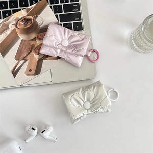 Close-up of heart-quilted AirPods case with circular hook in pink and cream finish