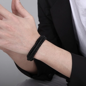 Detail of black woven leather bracelet on wrist paired with formal business attire