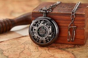 Close-up of vintage hollow compass pocket watch on antique world map background