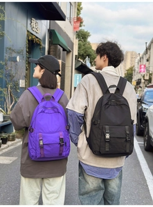 Vista trasera de mochilas de negocios impermeables púrpuras y negras en la ciudad