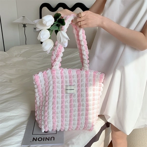 Detail of pink and white striped popcorn fabric tote bag with textured ruffles and label