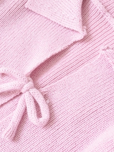 Macro detail of pink knitted top with polo collar and matching ribbon bow tie texture