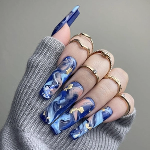 Close-up of long blue and pink marble press-on nails with gold foil and rings
