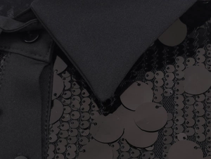 Detail of black sequins on mesh fabric with a close-up of the lapel and button