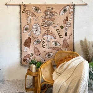 Detail of bohemian mushroom cotton blanket with tassels hanging on a white wall