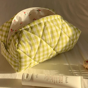 Macro detail of quilted green checkered cosmetic bag with red cherry lining and zipper