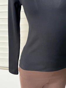 Dettaglio maglia nera a maniche lunghe con scollo a U che mostra la vestibilità aderente