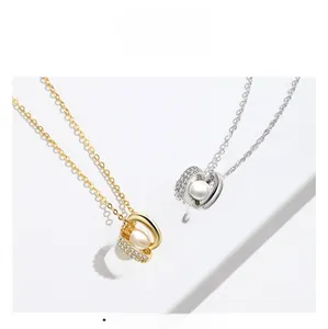 Macro shot of gold and silver necklaces featuring interlocking rings with zircon and pearl