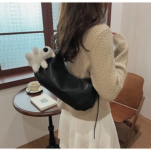 Fashionable black PU crescent bag with a cute white plush pendant accessory on shoulder strap
