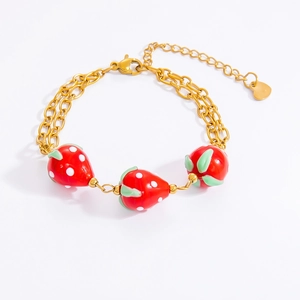 Detail of gold double-layer bracelet featuring red strawberry charms and heart pendant